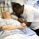 Nurse leaned in close to check a patient’s ear while they lay in a hospital bed.