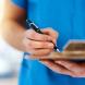 Close up of nurse writing on a clipboard.