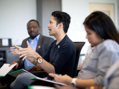 a group of three people, two males and one female, at a meeting having a discussion